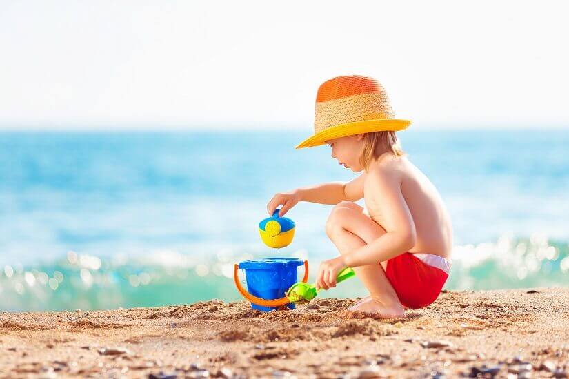 Kind mit Spielzeug am Strand